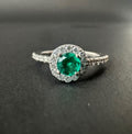 Ring with a round emerald in a halo and diamonds on the band (Ref. 292)
